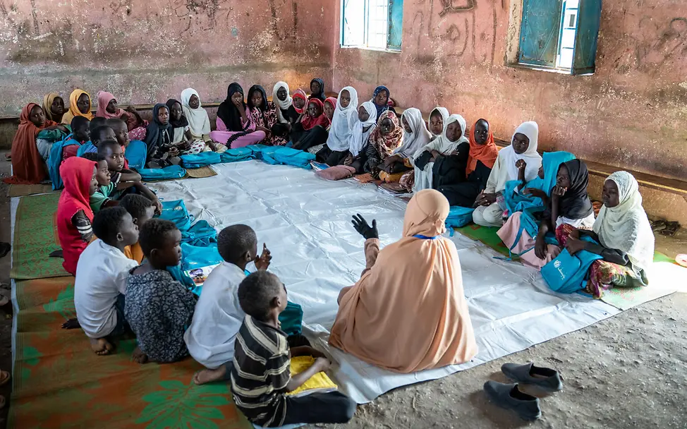 Eine psychosoziale Sitzung im Makanna von Gedaref. | © UNICEF/UNI971415/Saif Kinder sitzen auf dem Boden und sprechen zusammen