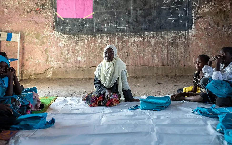 Marwa erzählt von ihren Erlebnissen. | © UNICEF/UNI971423/Saif Kinder sitzen vor einer Tafel auf dem Boden