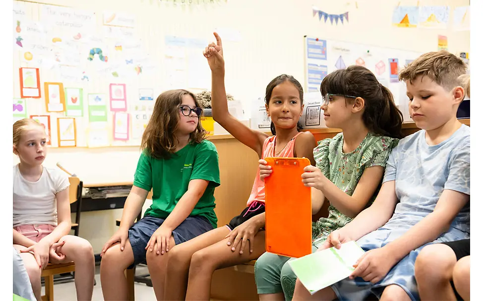 Kinderrechte im Schulalltag: Mehrere Kinder sitzen im Klassenraum, ein Kind meldet sich und die Gruppe hört zu.