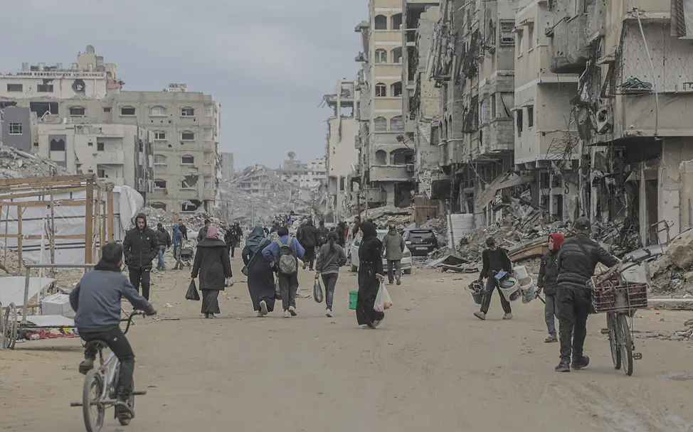 Gaza Spenden: Einwohner*innen von Gaza-Stadt sind zwischen den Trümmern der zerstörten Stadt unterwegs. 