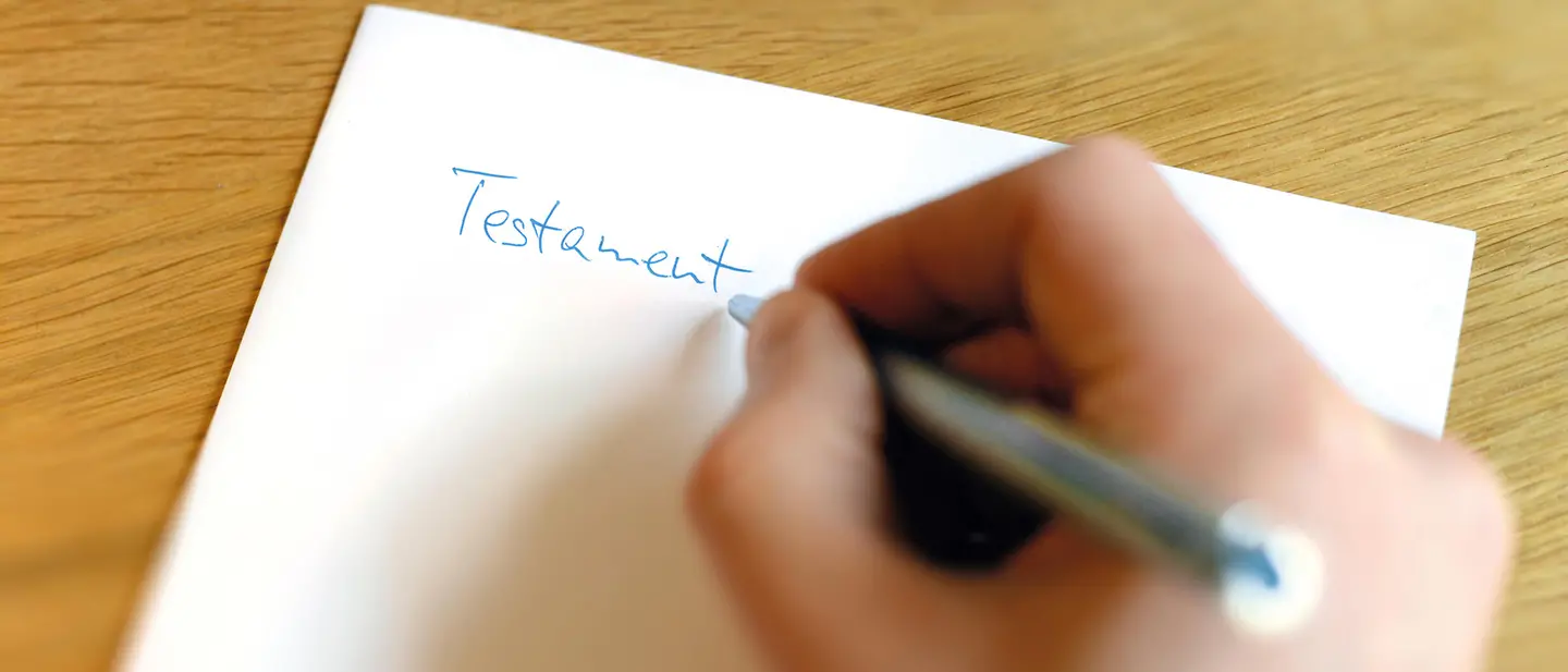Bei einem handschriftlich erstellten Testament gibt es einige Dinge zu beachten. | © UNICEF/Sachse-Grimm Testament erstellen: Eine Hand schreibt „Testament“ auf ein Blatt Papier.