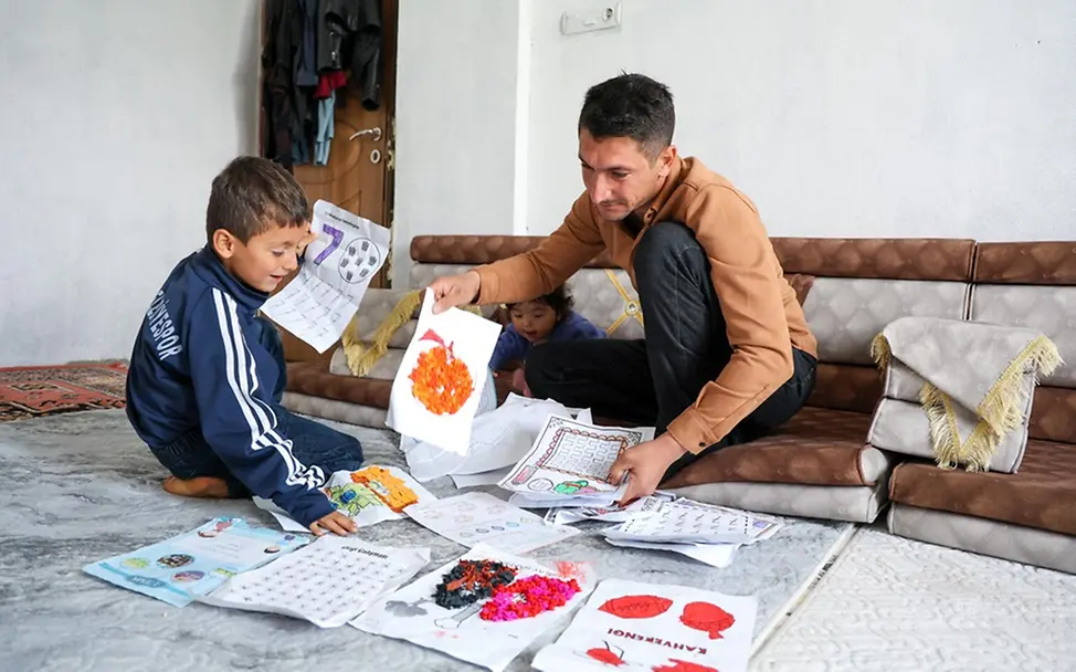 Rohat (6) und sein Vater Ferhat schauen sich gemeinsam Rohats Zeichnungen an. | © UNICEF/Kiliç Kindererziehung Tipps: Rohat (6) und sein Vater Ferhat schauen sich gemeinsam Rohats Zeichnungen an.