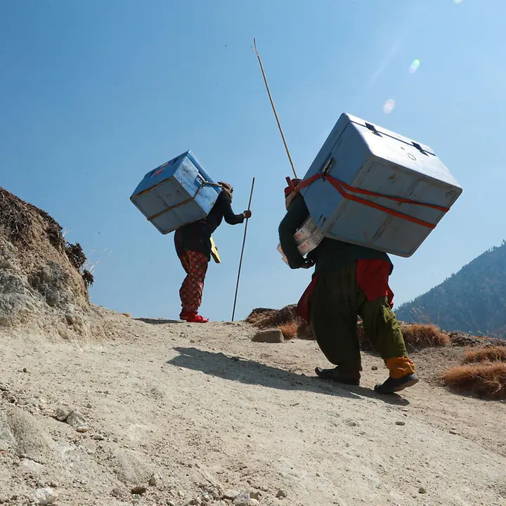 Zwei Männer in Nepal bringen zu Fuß Corona-Impfstoffe in abgelegene Bergregionen | © UNICEF/Laxmi-Prasad-Ngakhusi 80 Jahre UNICEF Jubiläum: UNICEF sorgt dafür, dass Corona-Impfstoffe auch Länder wie Nepal erreichen.