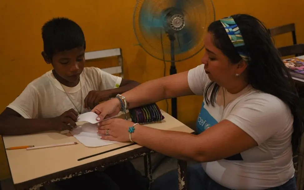 Wissen über Menstruation vermitteln: Eine UNICEF-Mitarbeiterin spricht in Venezuela mit einem Jungen über die Periode