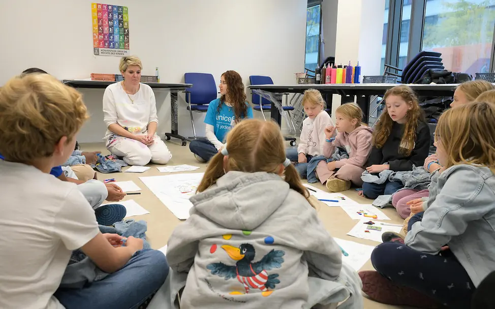 Grundgesetz einfach erklärt: In Deutschland ist es ein Grundrecht, dass sich Menschen friedlich versammeln dürfen | © UNICEF Grundgesetz einfach erklärt: Kinder sitzen in einem Kreis zusammen und sprechen.