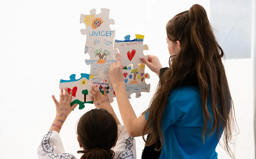 Ehrenamtliches Engagement für UNICEF: Engagierte bastelt zusammen mit einem Mädchen.