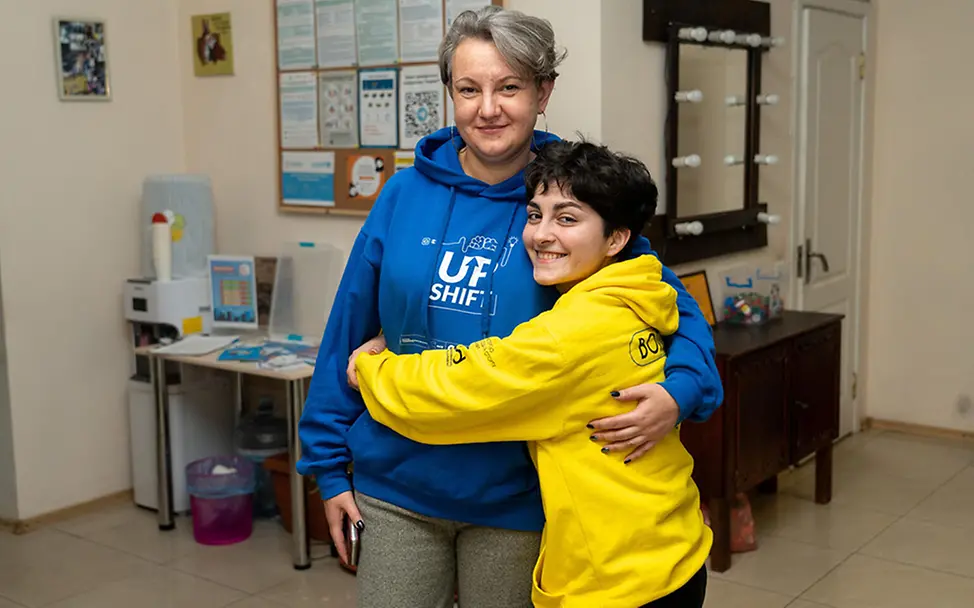Ehrenamtlich engagieren für UNICEF: Ein Kind umarmt eine ehrenamtlich Engagierte. 