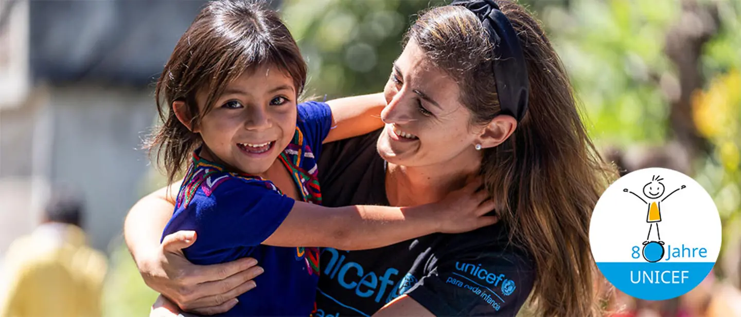 Ein Mädchen in Guatemala umarmt lächelnd eine UNICEF-Mitarbeiterin | © UNICEF/Flores 80 Jahre UNICEF Jubiläum: Das Kinderhilfswerk UNICEF feiert 80-jähriges Bestehen. 80 Jahre Einsatz für Kinder weltweit!
