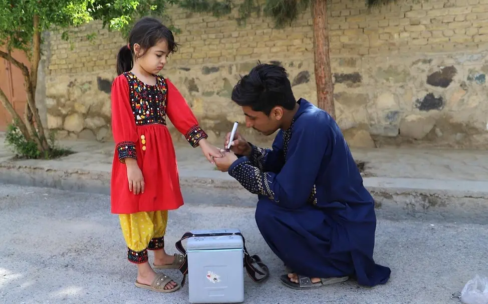 UNICEF unterstützt Gesundheitszentren auf der ganzen Welt mit Impfstoffen und medizinischem Equipment. | © UNICEF Impfen einfach erklärt: Ein Gesundheitshelfer markiert den Finger eines geimpften Mädchens mit Farbe.