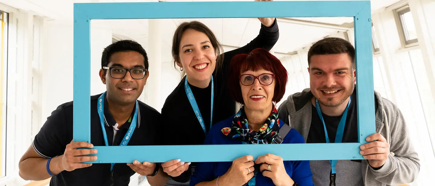UNICEF Ehrenamt: Vier Ehrenamtliche posieren für ein Portrait in einem Bilderrahmen.