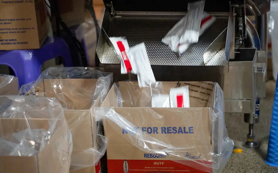 Erdnusspaste Herstellung: Beutel mit Erdnusspaste fallen aus einer Verpackungsmaschine in einen Karton.