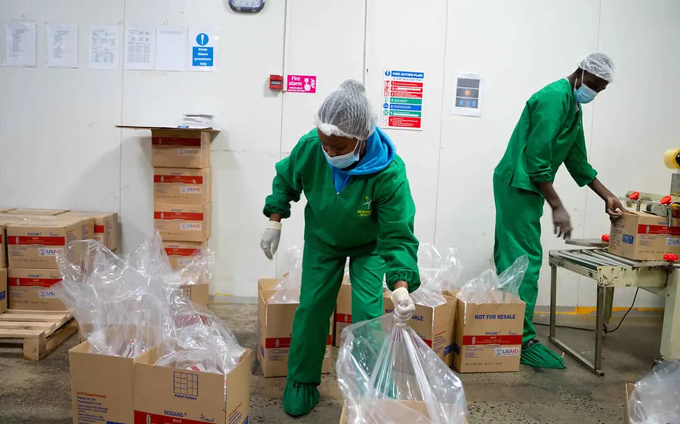 Erdnusspaste Herstellung: Zwei Mitarbeiter*innen in der RUTF-Fabrik verpacken Erdnusspaste in Kartons.