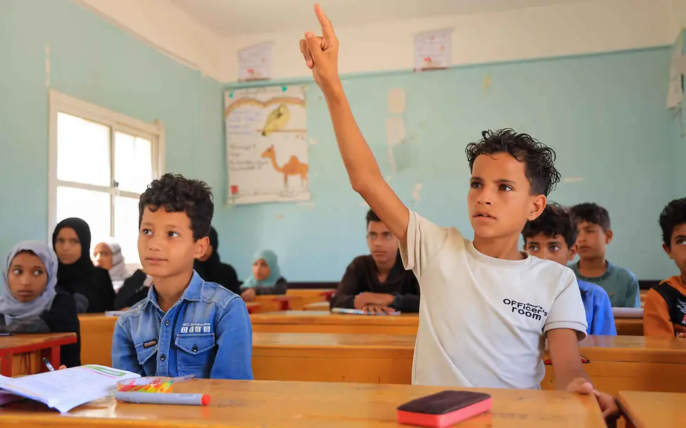 Bildung einfach erklärt: Ein Schüler im Klassenzimmer meldet sich.