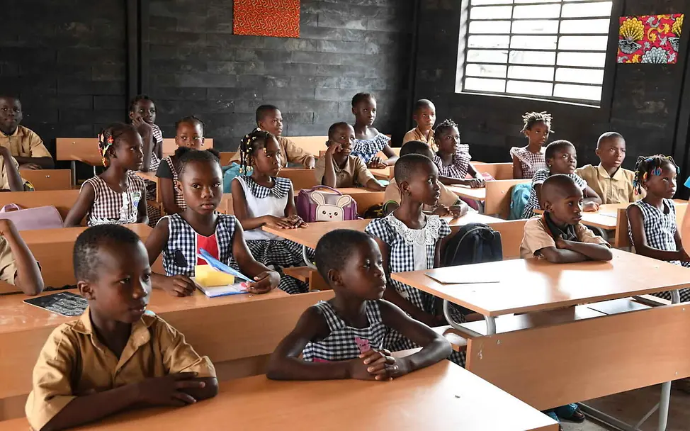 Bildung einfach erklärt: Kinder sitzen in einem Klassenraum, der aus recyceltem Plastik gebaut wurde.