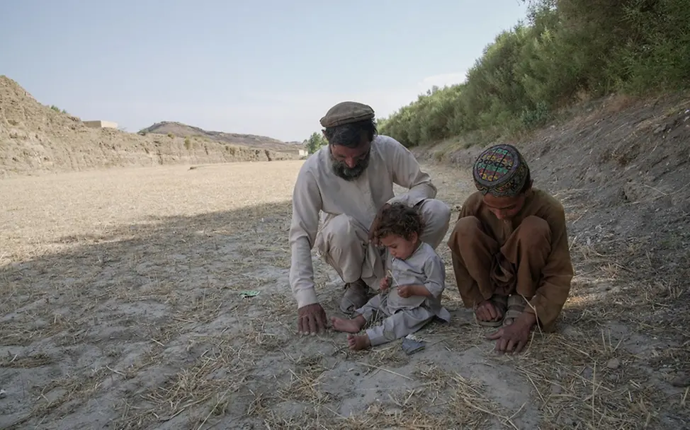 Baitullah, sein kleiner Bruder und sein Vater auf ihrem ausgetrockneten Land. | © UNICEF/Karimi Dürre: Folgen für Kinder & Ursachen: Baitullah, sein kleiner Bruder und sein Vater auf ihrem ausgetrockneten Land.