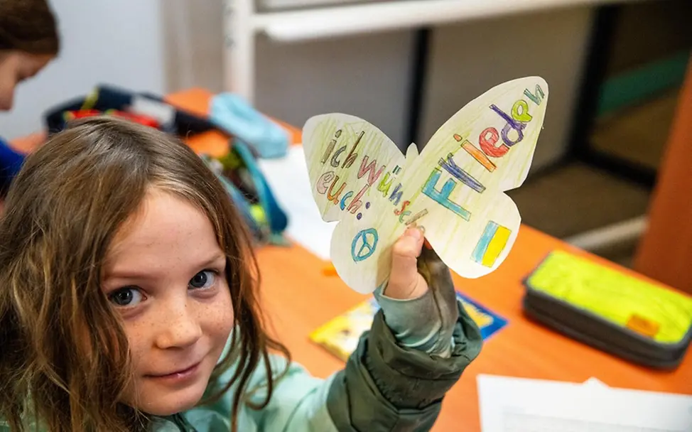 Ein Mädchen hat ihre Wünsche für die Kinder in der Ukraine auf einen Papier-Schmetterling geschrieben